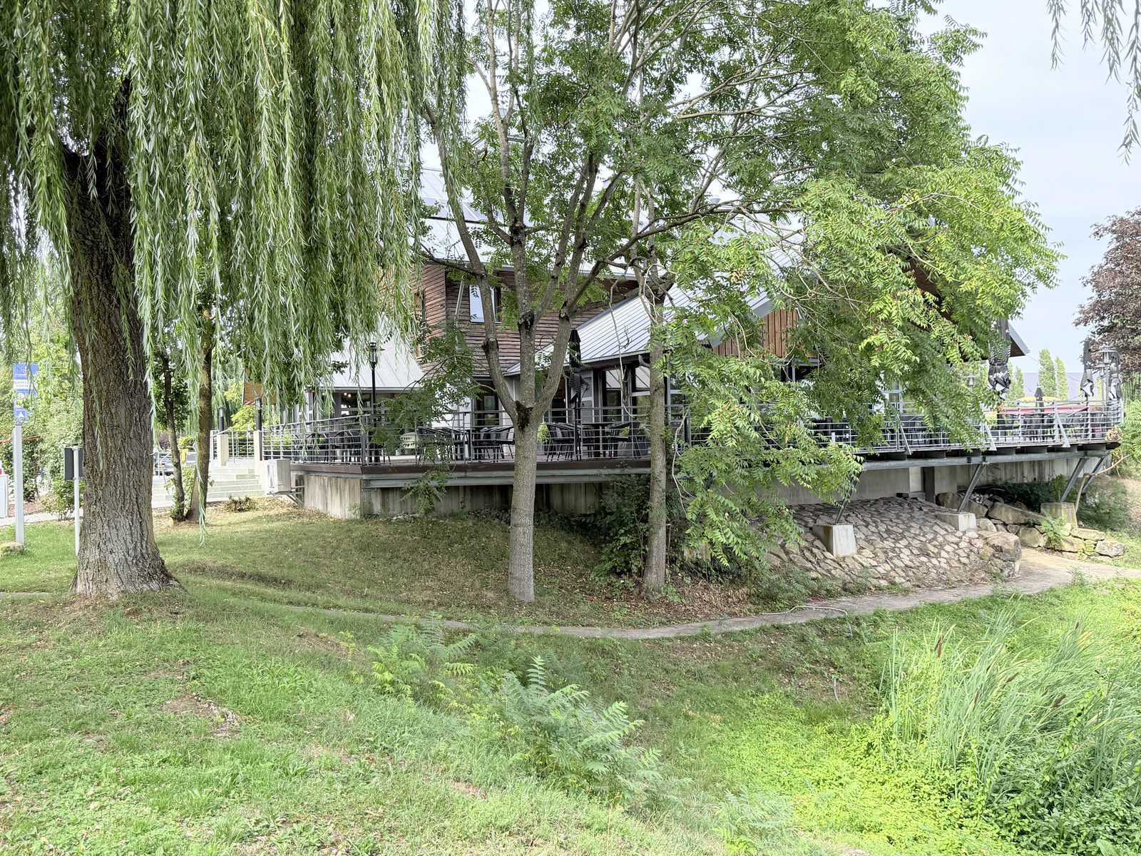 Terrasse des Hafenrestaurants unter alten Bäumen