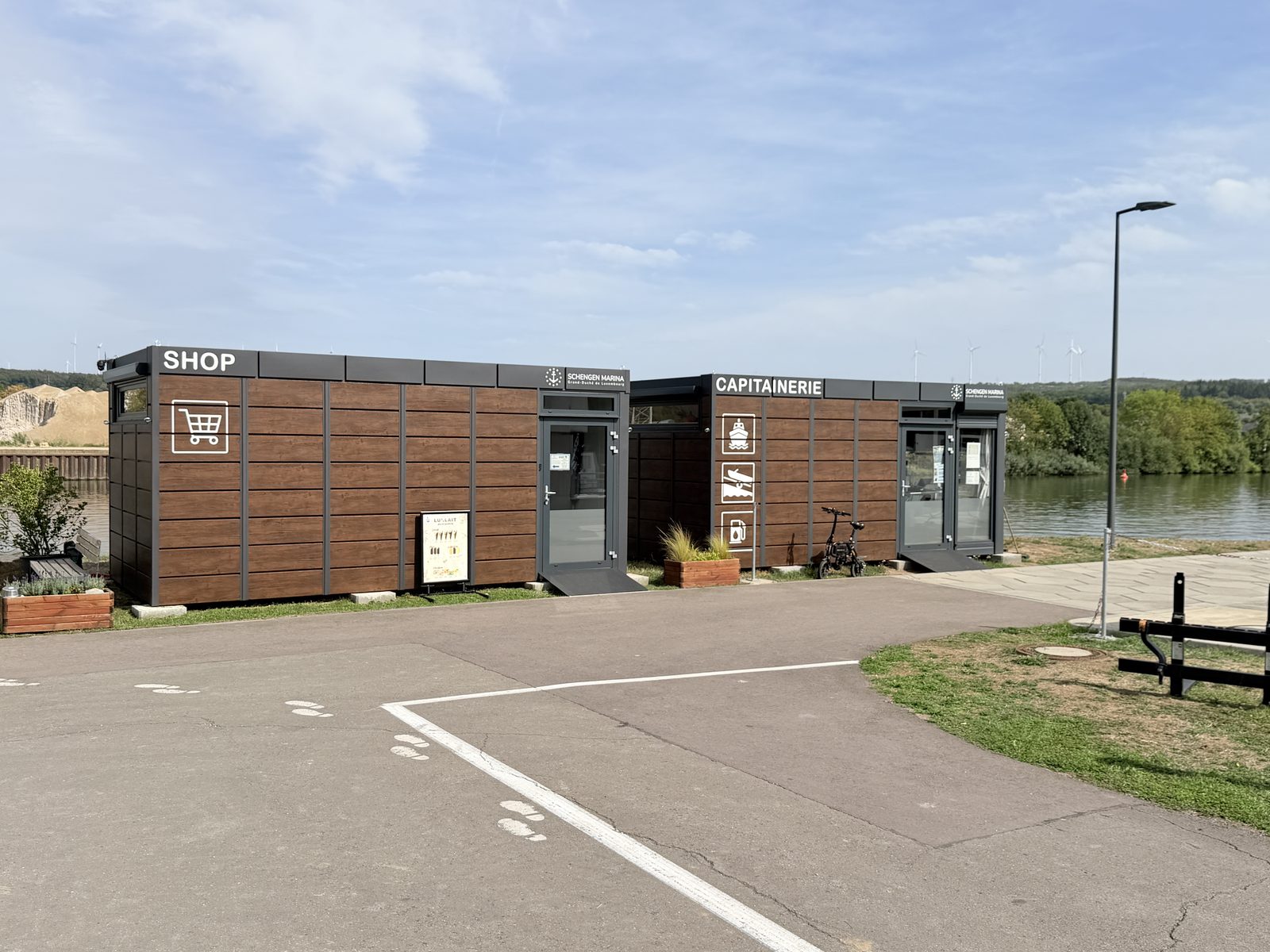 Shop und Hafenmeisterei der Schengen Marina, zwei flache Holzgebäude am Ufer